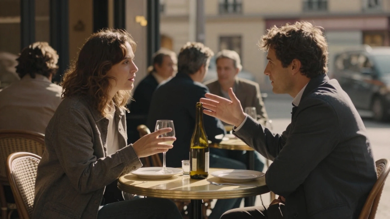 Two people having a quiet conversation at a Parisian café terrace, late afternoon light, wine glass on table.